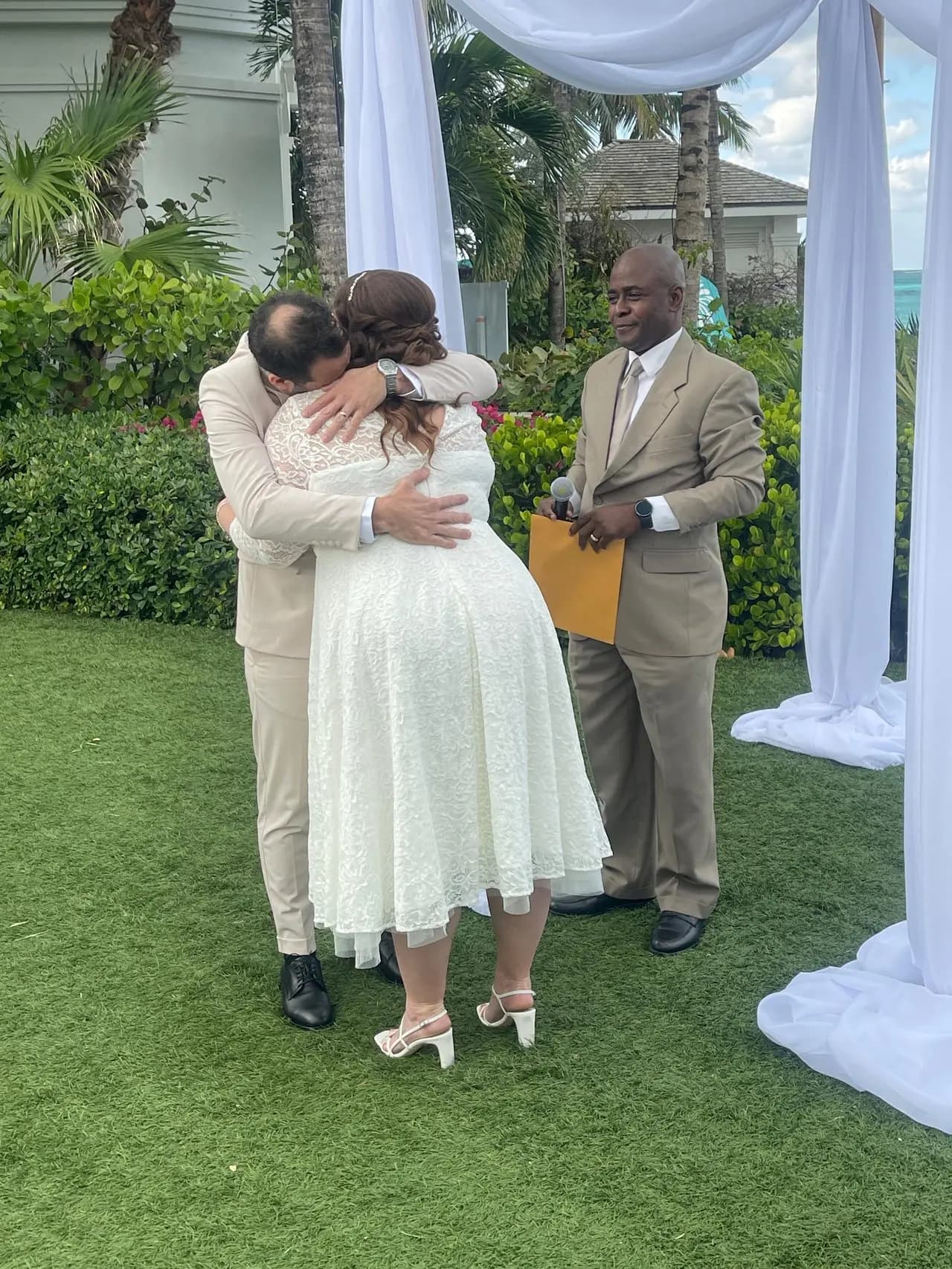 Antonio Beckford officiating a garden ceremony as the couple embraces.