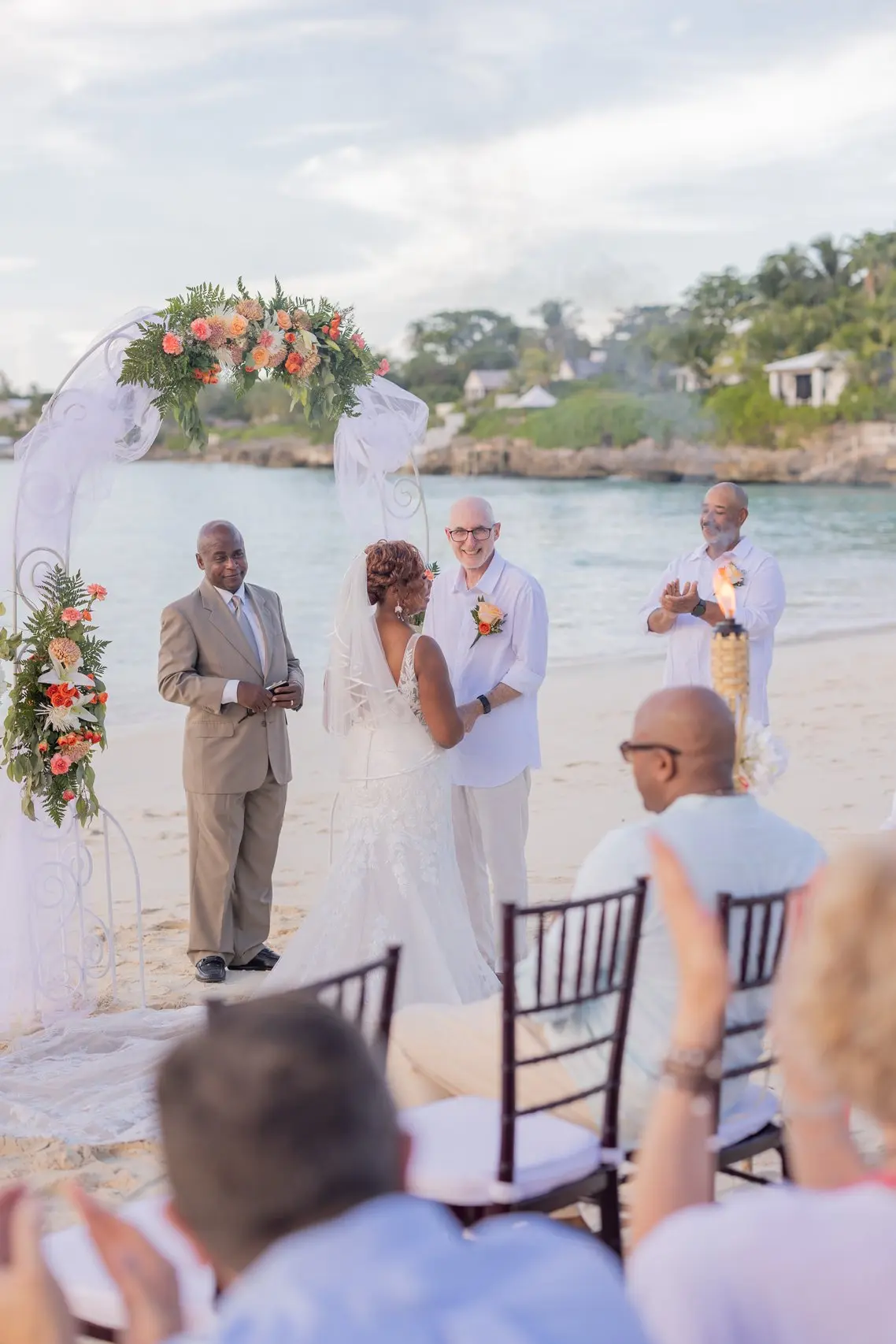 A resort beach ceremony with full guest rows and purple florals.